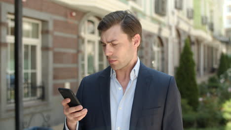 Closeup-businessman-typing-messages-at-street.-Man-using-smartphone-at-street