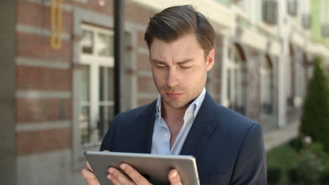 Closeup-man-holding-modern-touchpad-at-street.-Man-browsing-internet-on-tablet
