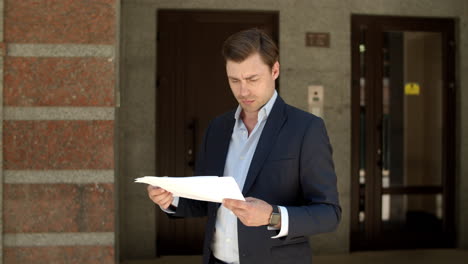Closeup-man-reading-documents.-Businessman-looking-at-documents-at-street