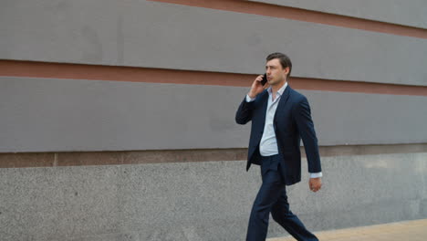 Side-view-businessman-talking-phone-at-street.-Man-talking-phone-with-partner