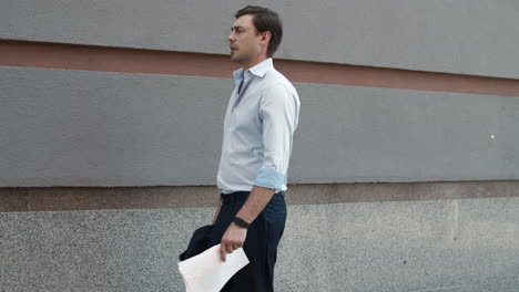 Closeup-businessman-walking-with-documents-at-street.-Man-holding-papers-outdoor