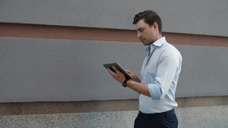 Closeup-businessman-walking-with-tablet.-Man-getting-good-news-on-tablet-outdoor
