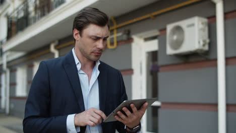 Closeup-business-man-using-tablet-at-street.-Man-working-on-touchpad-outdoors