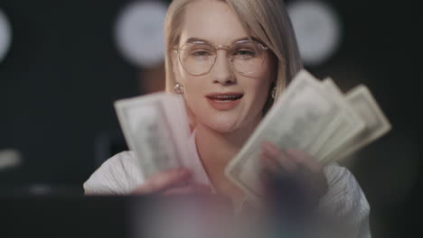 Satisfied-business-woman-counting-money-cash-in-dark-office