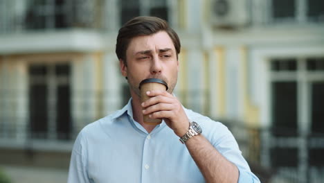 Closeup-businessman-drinking-coffee-at-street.-Man-looking-away-at-street
