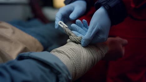 Doctor-giving-first-aid-help-to-patient.-Paramedic-applying-bandage-on-man-arm