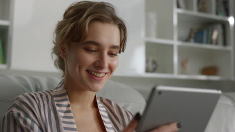 Portrait-smiling-woman-reading-good-news-holding-tablet-computer-at-home.