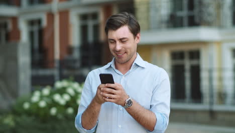 Portrait-businessman-using-smartphone.-Man-typing-messages-on-phone-outside
