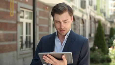 Closeup-businessman-browsing-internet-outdoors.-Man-holding-touchpad-at-street