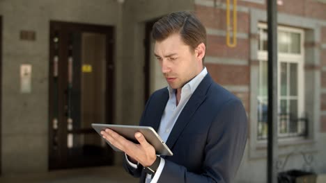 Closeup-businessman-using-tablet-outdoors.-Man-browsing-internet-in-at-street