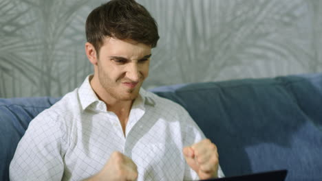 Angry-man-clenching-fists-in-front-of-computer.-Annoyed-guy-working-on-laptop.