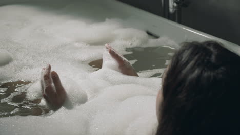Unknown-lady-taking-bath-in-luxury-hotel.-Back-view-woman-lying-in-home-bathtub