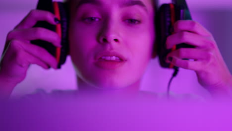 Esport-girl-wearing-cyber-headphones-before-round-in-pink-neon-lights-closeup.
