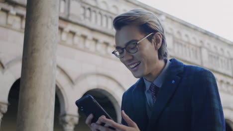 Student-using-smartphone.-Smiling-businessman-browsing-internet-outdoors
