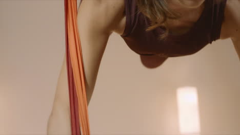 Sports-woman-hanging-upside-down-in-hammock.-Girl-practicing-fly-yoga-in-studio