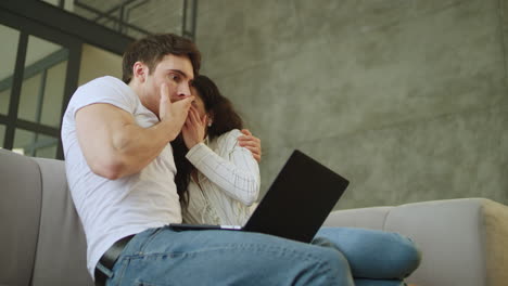 Portrait-of-scared-couple-watching-laptop-computer-at-home-in-slow-motion.