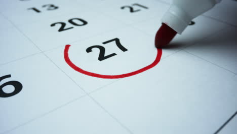 Business-working-day-calendar.-Woman-marking-day-on-calendar-with-marker