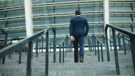 Back-view-stylish-man-going-upstairs-in-suit-at-street.-Successful-businessman
