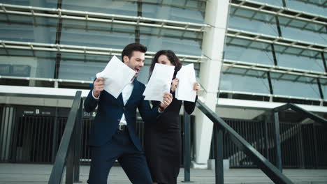 Couple-throwing-papers-in-slow-motion.-Business-man-and-woman-hugging-outdoors