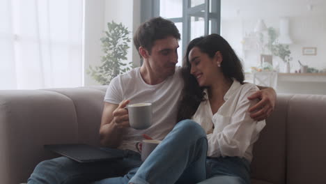 Happy-couple-drinking-coffee-at-home-.-Sexy-man-and-woman-talking-at-sofa.
