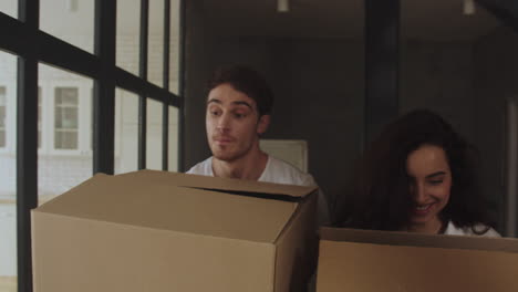 Closeup-couple-moving-to-new-apartment-with-paper-boxes-in-slow-motion.
