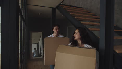 Portrait-of-young-married-couple-with-boxes-walking-at-home.
