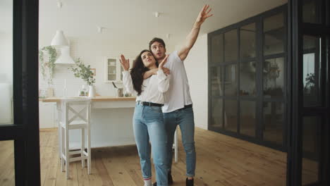 Happy-homeowners-planning-house-interior.-Young-married-couple-hugging-at-home.