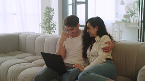 Happy-couple-watching-laptop-at-home.-Young-man-and-woman-relaxing-on-sofa