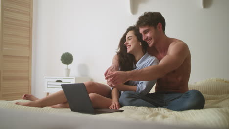 Relaxed-couple-watching-laptop-at-home.-Cheerful-couple-laughing-near-computer