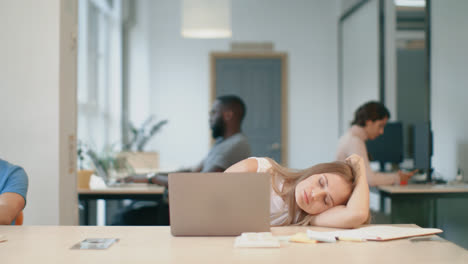 Tired-woman-sleeping-at-workplace.-Sleepy-lady-laying-at-table-with-notebook.
