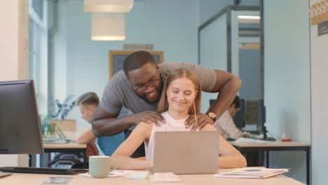 Pretty-woman-working-on-computer-at-coworking.-Black-man-making-massage