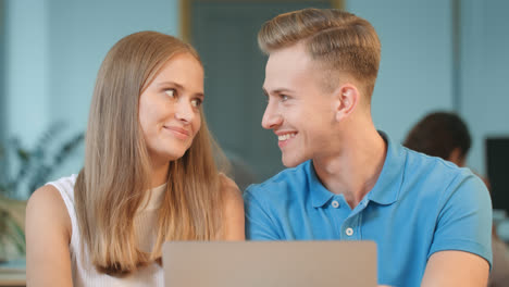 Young-man-flirting-with-girl-at-office.-Happy-colleagues-smiling-to-each-other