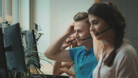 Young-operator-putting-headset-in-call-center.-Smiling-man-talking-with-client