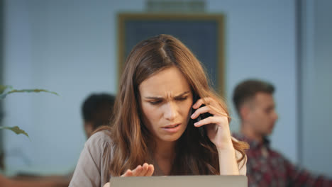 Unhappy-business-woman-talking-on-mobile-phone-at-coworking-space.-Angry-woman