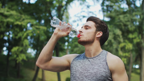 Sport-man-drinking-water-from-bottle-after-running-exercise-in-summer-park