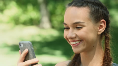 Cheerful-woman-using-mobile-phone-while-morning-run-in-summer-park