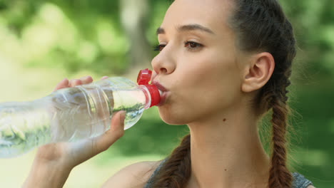 Mujer-Fitness-Bebiendo-Agua-De-Una-Botella-Después-De-Hacer-Ejercicio-En-El-Parque-De-La-Ciudad