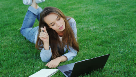 Young-woman-using-laptop-computer-for-freelance-work-in-park