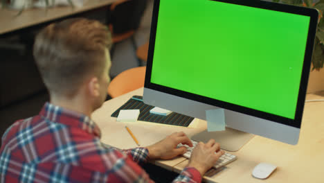 Business-man-typing-on-computer-with-green-screen.-Young-man-working-on-computer
