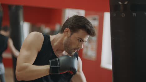 Fitness-man-training-box-kick-in-sport-club.-Boxer-kicking-boxing-bag-in-gloves.