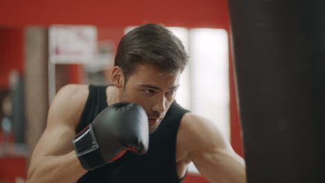 Hombre-Kickboxer-Entrenando-Golpes-En-Bolsa-De-Combate-En-Club-De-Lucha.