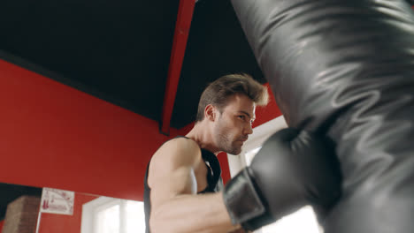 Boxer-man-kicking-combat-bag-in-gym-low-angle-view.
