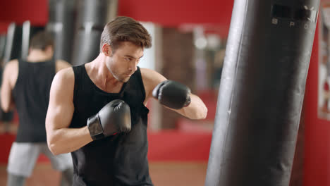 Man-boxer-punching-combat-bag-in-boxing-club.-Closeup-sportsman-training-kick.