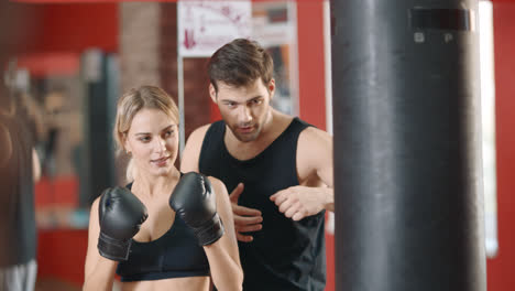 Personal-trainer-training-woman-at-boxing-workout-in-sport-club.