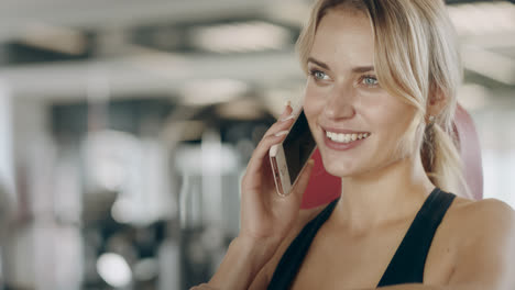 Beautiful-woman-talking-smartphone-in-fitness-gym.-Smiling-girl-having-break
