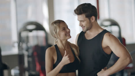 Happy-couple-showing-thumbs-up-gesture-after-successful-training-in-fitness-club