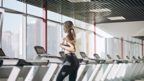 Fitness-woman-running-on-treadmill-in-gym.-Pretty-girl-having-cardio-training.