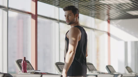 Handsome-man-looking-around-in-fitness-club.-Macho-male-walking-treadmill-in-gym