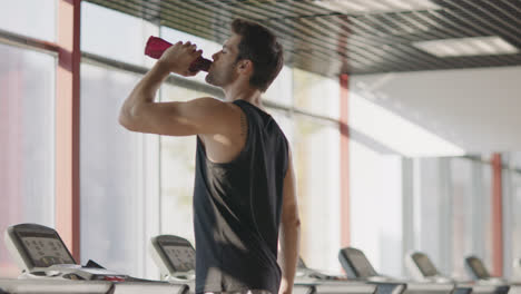 Athlete-man-drinking-water-at-cardio-training-on-treadmill-machine.