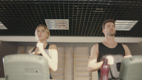 Sport-couple-training-run-on-treadmill-machine-in-fitness-club.